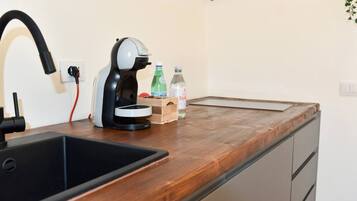 Una cucina con un lavello nero, una macchina da caffè, un piano di lavoro in legno e una piccola scatola di legno.