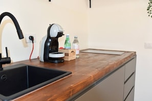 A kitchen with a black sink, a coffee maker, a wooden countertop, and a small wooden box.
