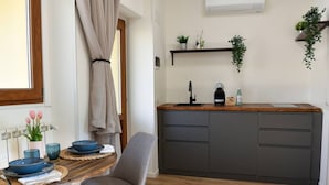 A modern kitchen with a wooden countertop, grey cabinets, and a window with curtains. - Fly&Rest MXP | Unit 2 | 24/7 Airport Transfer (Casorate Sempione)
