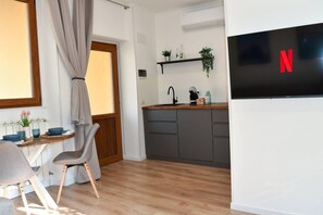 A modern kitchen with a built-in dishwasher, a coffee machine, and a TV mounted on the wall.