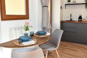A dining area with a wooden table, two blue bowls, a vase with pink flowers, and a grey chair.