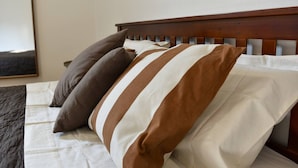 A bed with striped pillows and a wooden headboard. - Fly&Rest MXP | Unit 2 | 24/7 Airport Transfer (Casorate Sempione)