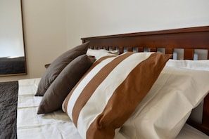 Un letto con cuscini a righe e una testiera in legno.