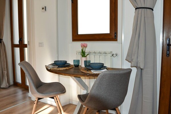 A dining area with a wooden table, two grey chairs, and a window with a view of the outside.