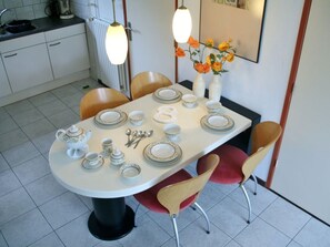 A dining table set with plates, bowls, and cutlery, surrounded by chairs. - Holiday Home With 2 Bedrooms (Sint Maartensvlotbrug)