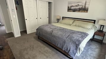 A bedroom with a bed, a nightstand, a dresser, and a closet.