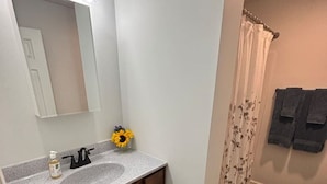Un bagno con lavandino, specchio e tenda doccia.