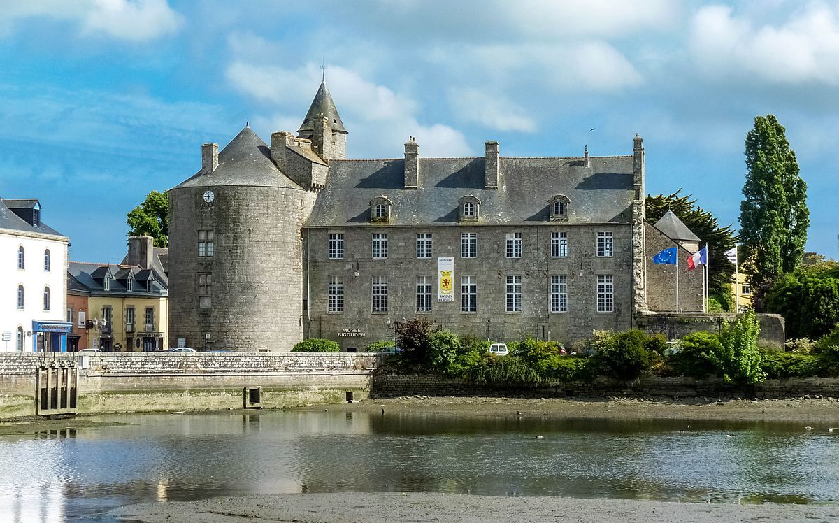 Un bâtiment historique en pierre, doté d’une tour, d’une enseigne indiquant qu’il s’agit d’un musée et de plusieurs drapeaux.