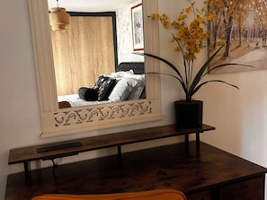 A wooden desk with a mirror, a potted plant, and a painting on the wall. - Old Cottages: 3 Bed (Ripon)