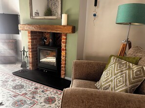 A cozy living room with a fireplace, a sofa, a patterned rug, and a lamp. - Old Cottages: 3 Bed (Ripon)