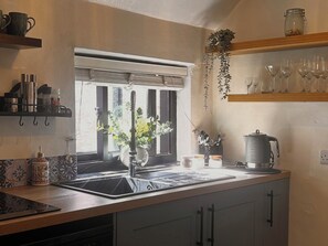 A kitchen with a window, sink, and various kitchen items. - Old Cottages: 3 Bed (Ripon)