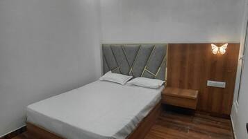 Un dormitorio con una cama, un banco de madera y una lámpara de pared.