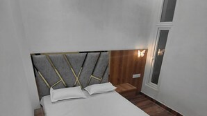 En säng med en gavel som har geometriska mönster, ett sängbord med en lampa och ett fönster med utsikt över omgivningen.