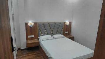 Ein modernes Schlafzimmer mit Bett, Holz-Kopfteil, Nachttischen und Deckenventilator.