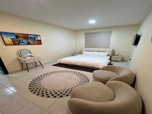 A bedroom with a bed, bedside tables, a round rug, and a seating area. - Cozy 1-bedroom apartment in peaceful Dubai with AC (Dubai)