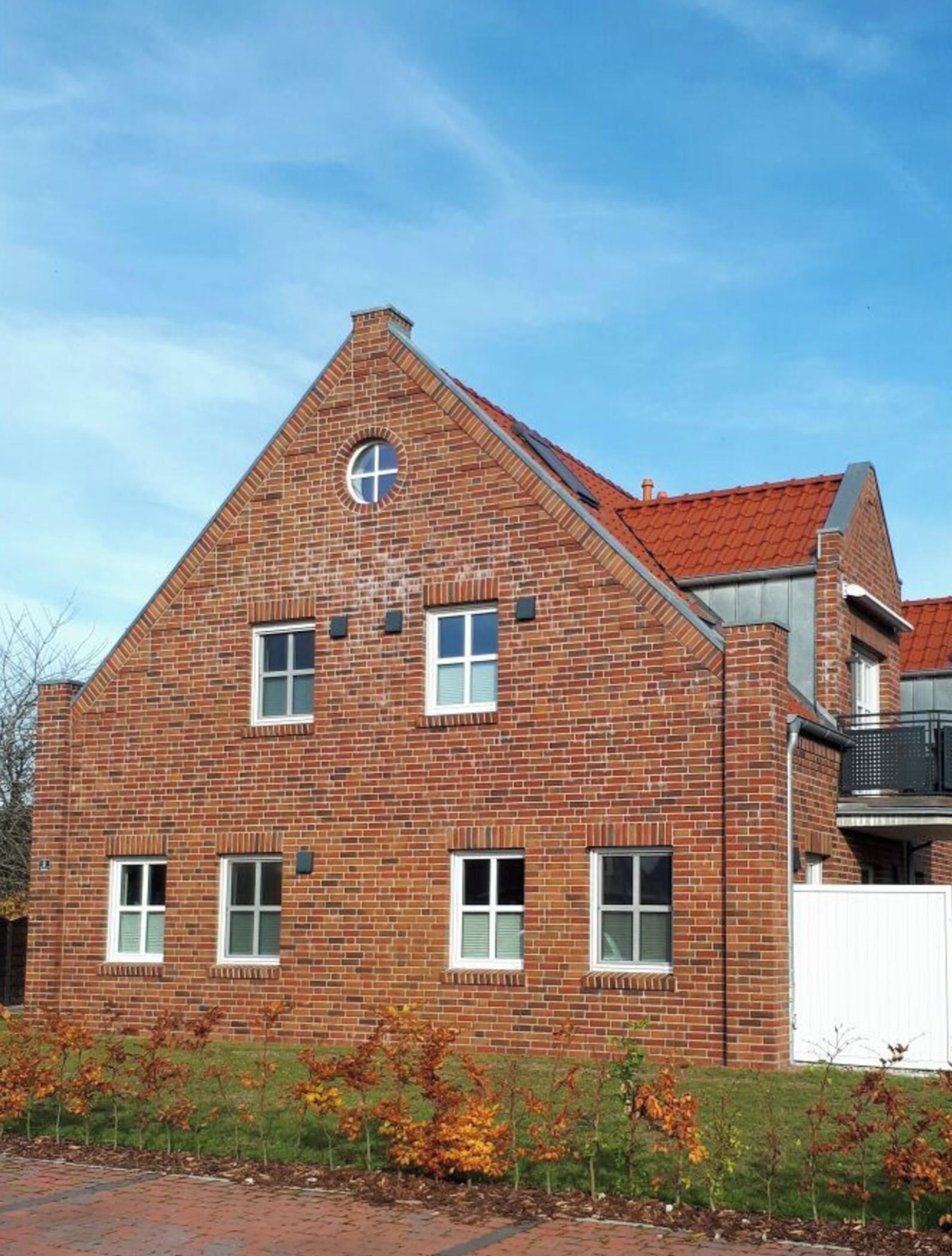 A red brick building with a gabled roof and a circular window.
