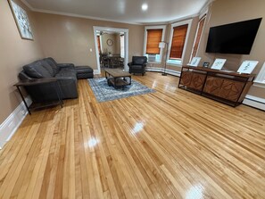 A living room with a sectional sofa, a coffee table, and a TV mounted on the wall. - Dog-Friendly 3BR Townhome · Parking & Workspace (Southbridge)