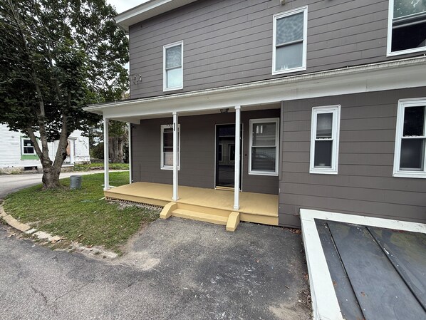 A two-story house with a covered porch and a front door. - Dog-Friendly 3BR Townhome · Parking & Workspace (Southbridge)