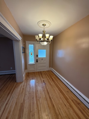 A hallway with wooden flooring, a white door with a stained glass window, and a chandelier. - Dog-Friendly 3BR Townhome · Parking & Workspace (Southbridge)