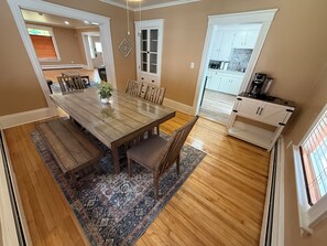 A dining area with a wooden table and chairs, a rug, and a kitchen in the background. - Dog-Friendly 3BR Townhome · Parking & Workspace (Southbridge)