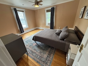 A bedroom with a bed, a dresser, a ceiling fan, and two windows with curtains. - Dog-Friendly 3BR Townhome · Parking & Workspace (Southbridge)