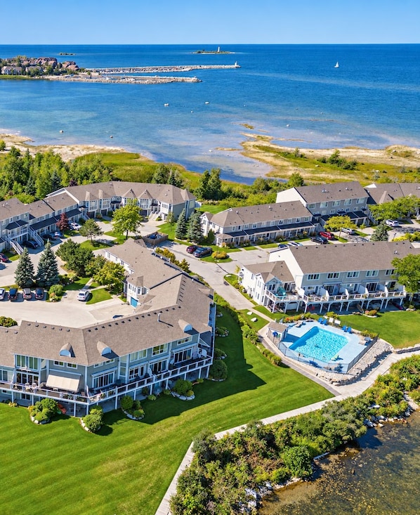 Área residencial costeira com várias casas de dois andares, uma piscina grande e vista para o mar.