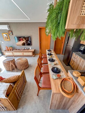 A modern kitchen with a long dining table, wooden chairs, and a built-in refrigerator. - Casa Linda a poucos passos do mar (Sao Miguel dos Milagres)