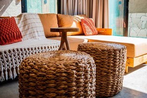 A modern living room with a sofa, ottomans, and a small wooden table. - Casa Linda a poucos passos do mar (Sao Miguel dos Milagres)