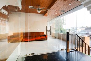 Un intérieur moderne avec un mur de verre, un plafond en bois, un plancher noir et un canapé rouge.