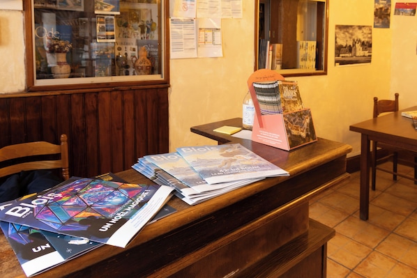 Tauleller de recepció amb revistes, una ampolla d'aigua i un quadre al mur.