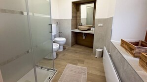 A bathroom with a glass shower enclosure, a toilet, a sink with a mirror above, and a wooden vanity. - Fly&Rest MXP | Suite | Airport Transfer 24/7 (Casorate Sempione)