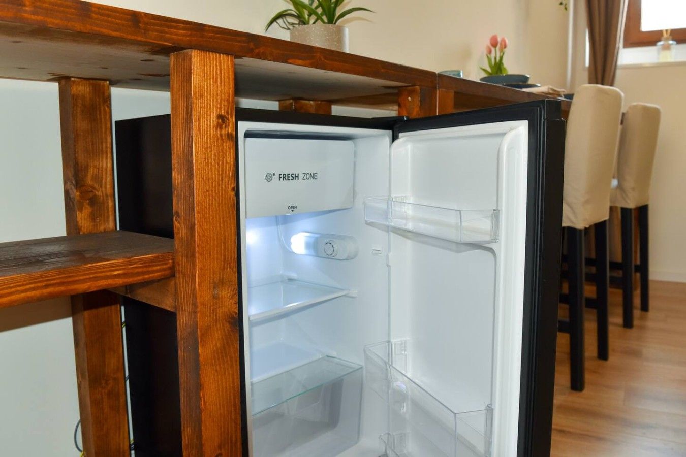 Une cuisine moderne dotée d’un réfrigérateur encastré, d’une table en bois et de chaises.