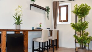 A compact kitchenette with a black refrigerator, a wooden countertop, and two chairs. - Fly&Rest MXP | Suite | Airport Transfer 24/7 (Casorate Sempione)
