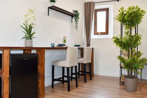 A compact kitchenette with a black refrigerator, a wooden countertop, and two chairs. - Fly&Rest MXP | Suite | Airport Transfer 24/7 (Casorate Sempione)