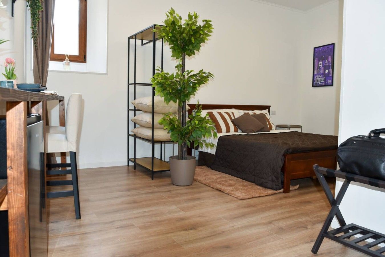 Une chambre à coucher avec un lit, un bureau, une chaise, une plante en pot et une petite table.