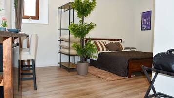 Une chambre à coucher avec un lit, un bureau, une chaise, une plante en pot et une petite table.