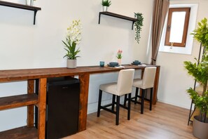 A compact kitchen with a wooden countertop, a black refrigerator, and two chairs.