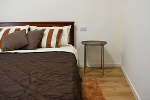 Une chambre à coucher avec un lit, des oreillers, une petite table ronde et un tapis marron.
