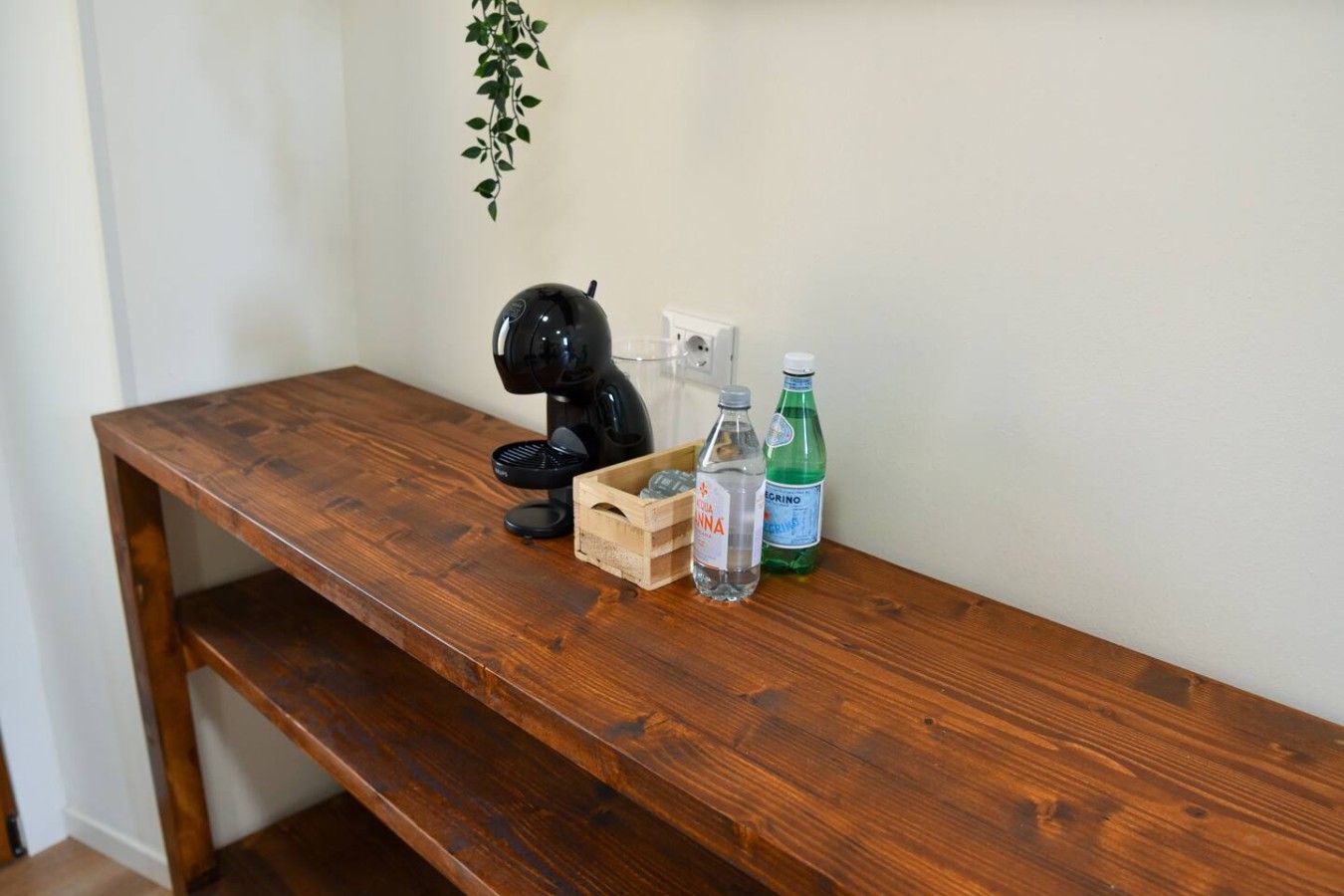 Un bureau en bois sur lequel se trouvent un objet noir, une bouteille et une bouteille verte.