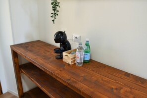 A wooden desk with a black object, a bottle, and a green bottle.