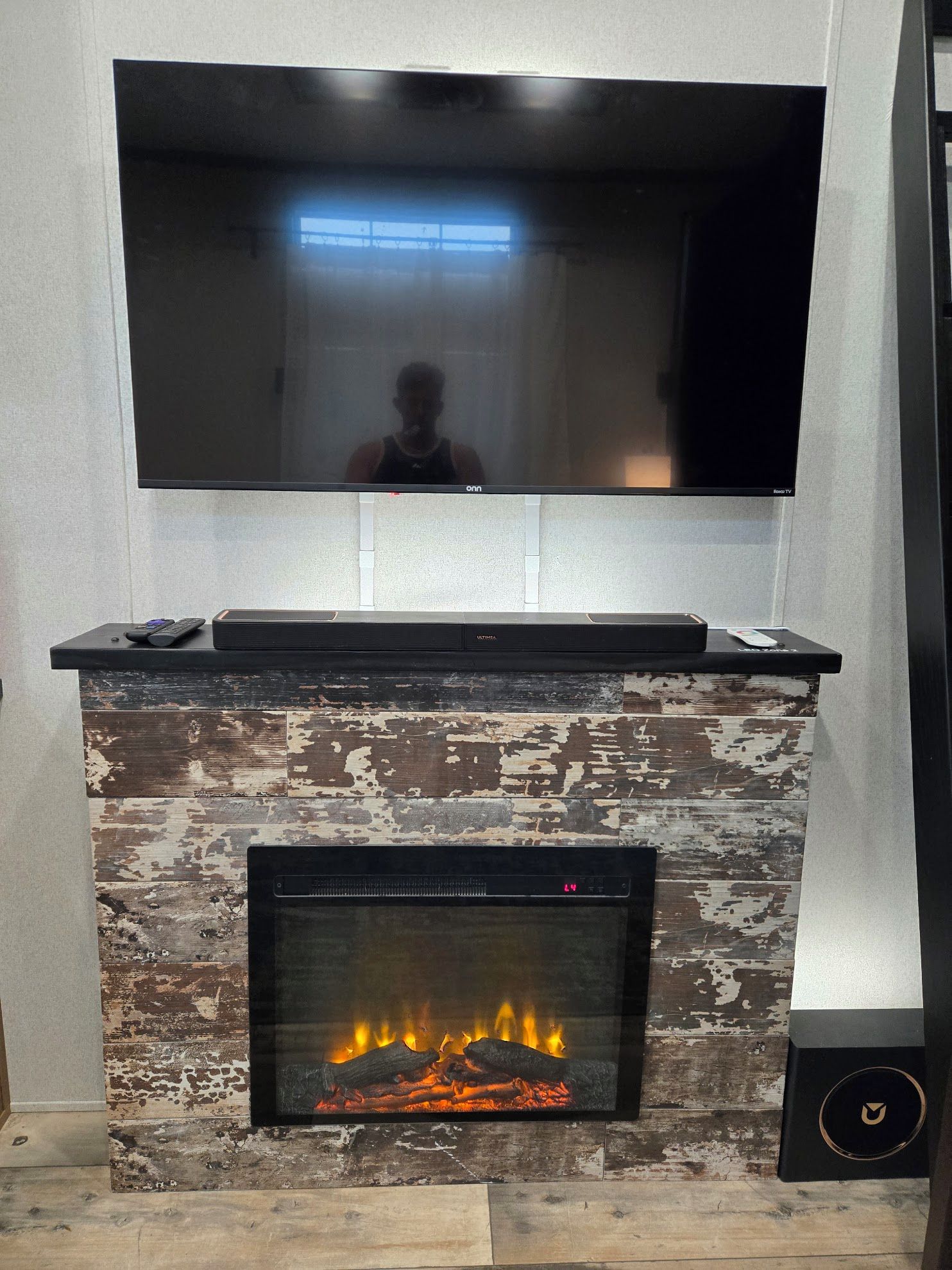 A flat-screen TV mounted above a fireplace with a visible fire.