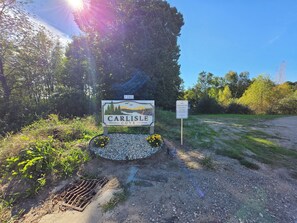 A sign for Carlisle Cove with a number 1362, a gravel path, and surrounding greenery.