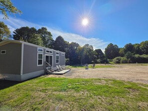Une maison mobile de plain-pied dotée d’une véranda et d’un espace extérieur aménagé pour s’asseoir.