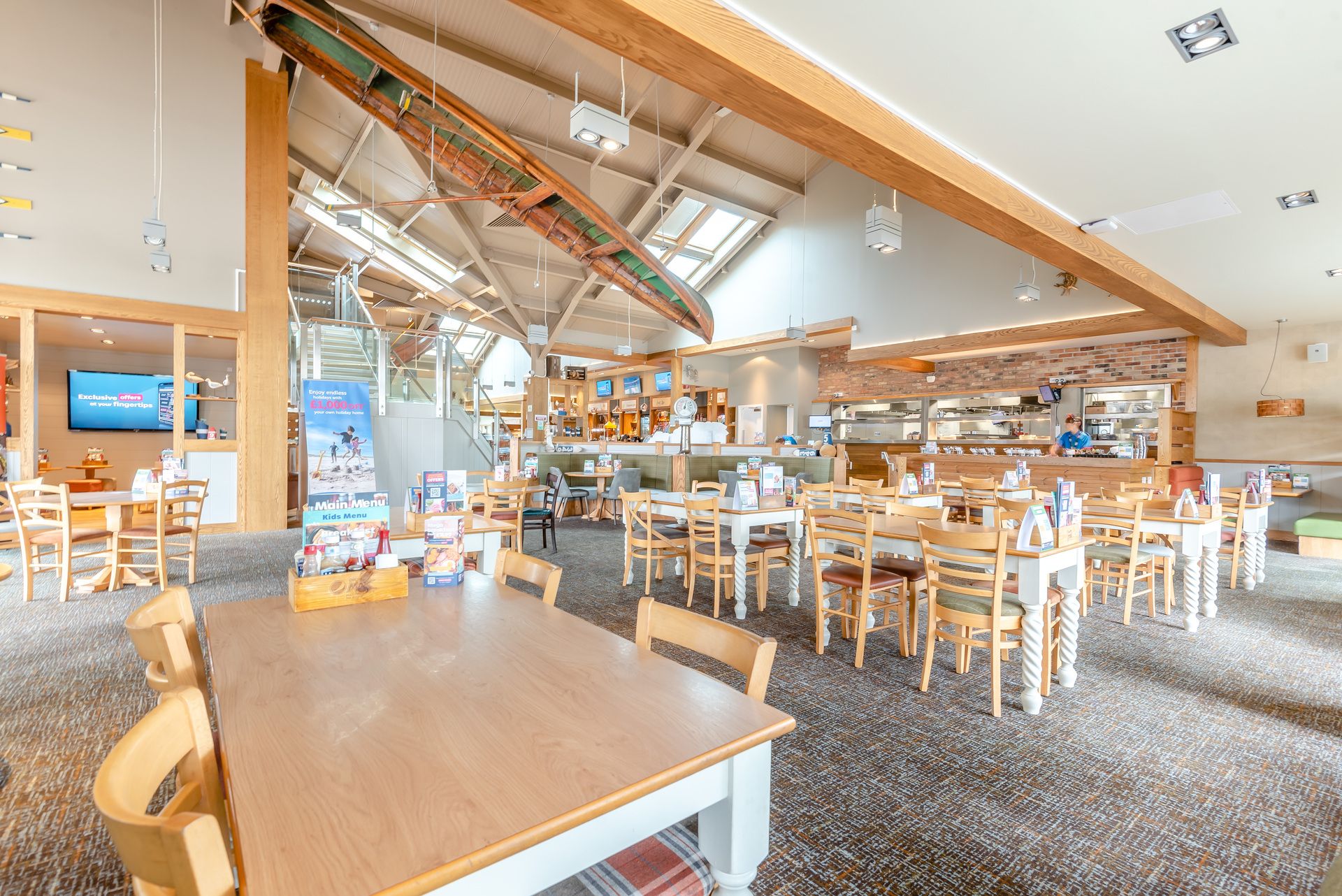A spacious restaurant with high ceilings, exposed beams, and a variety of seating arrangements including tables and booths.