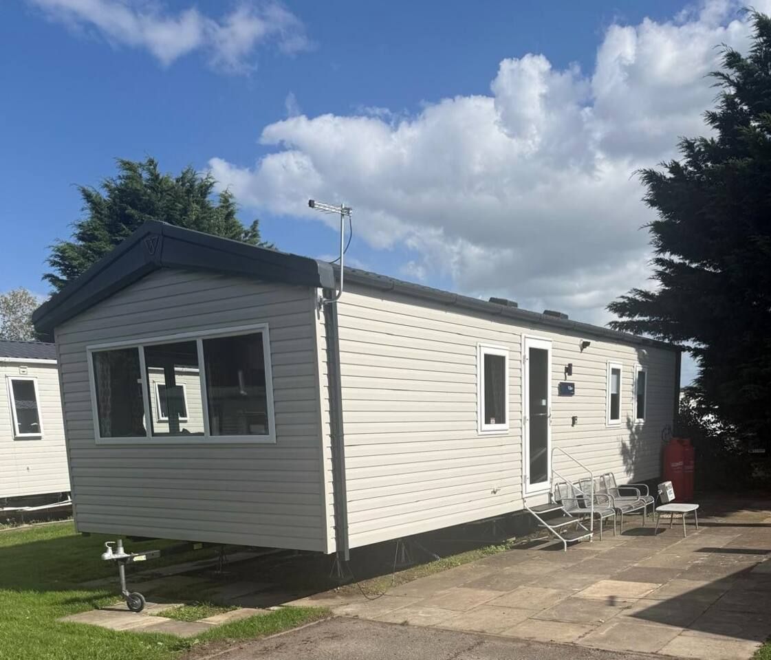A single-story mobile home with a front porch, a small attached garage, and a clear sky.