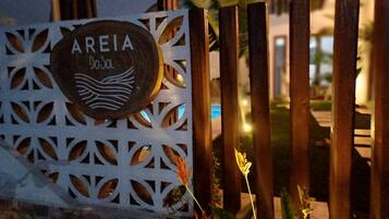 A sign with the name 'AREIA' and a logo, set against a decorative white metal fence with vertical wooden slats.