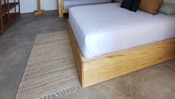 Quarto com beliche, ventilador de teto, cabideiro de madeira e janela.