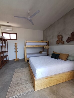 A bedroom with a bunk bed, a ceiling fan, a wooden coat rack, and a window.