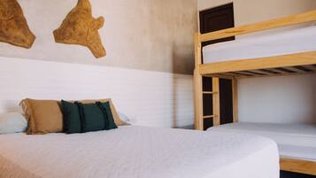 A bunk bed room with a white bedspread, two pillows, and a wooden ladder.
