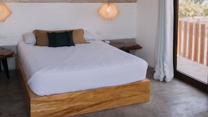 Une chambre dotée d’un grand lit, d’un ventilateur de plafond, de deux lampes fixées au mur et offrant une vue sur l’extérieur.